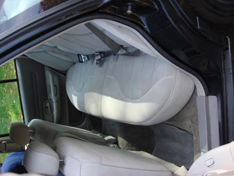 2003 Ford Crown Victoria - Interior view of a car's rear bench seat and front seats, showing gray cloth upholstery and seatbelts.