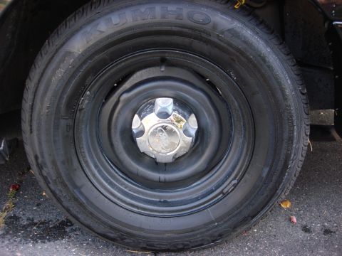 2003 Ford Crown Victoria - Close-up of a wheel and tire assembly, a Kumho tire and a chrome hubcap with a Ford logo.