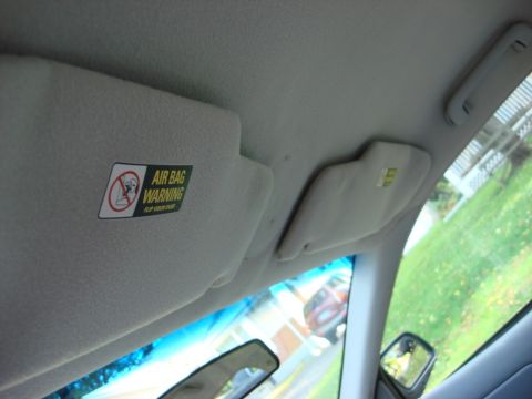2003 Ford Crown Victoria - The interior of a vehicle is shown, focusing on the sun visor and an air bag warning label.