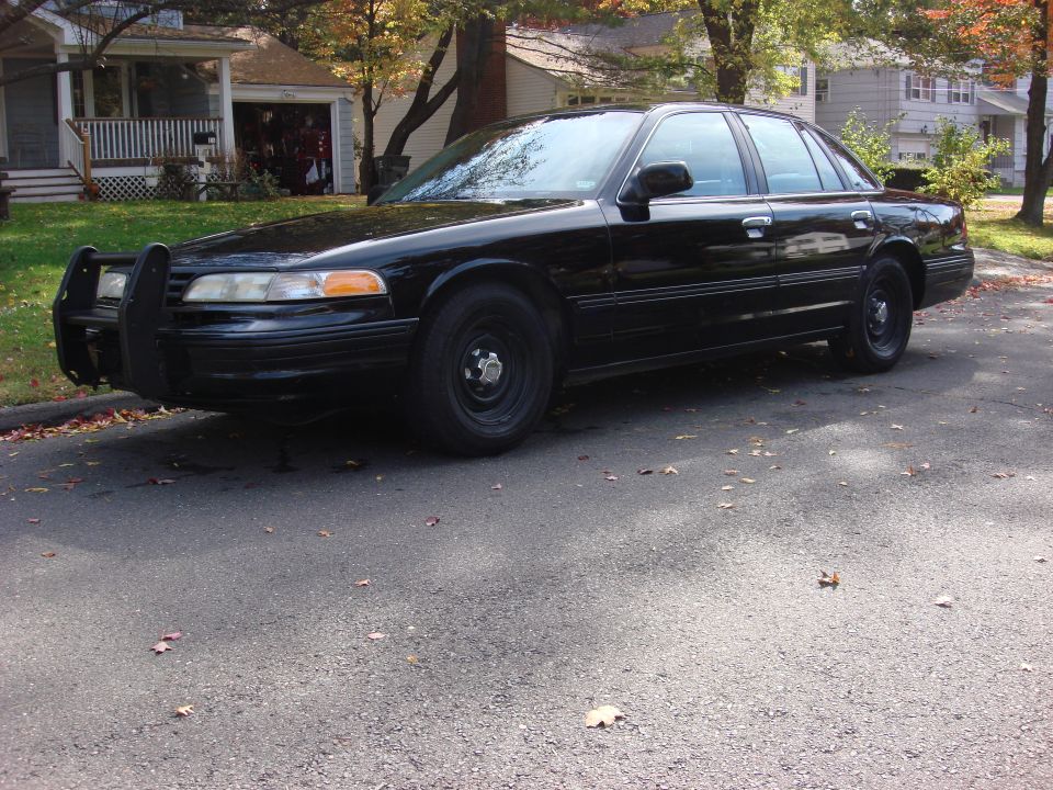 Black 2003 Ford Crown Victoria with a push bumper parked on a street