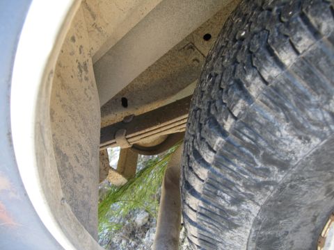 1979 Ford Bronco - Close-up view of the rear tire and suspension system of a vehicle.