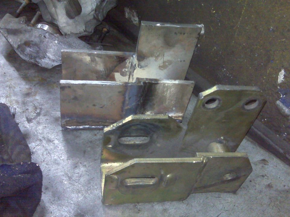 Welded metal brackets on a workbench, possibly for a vehicle lift kit