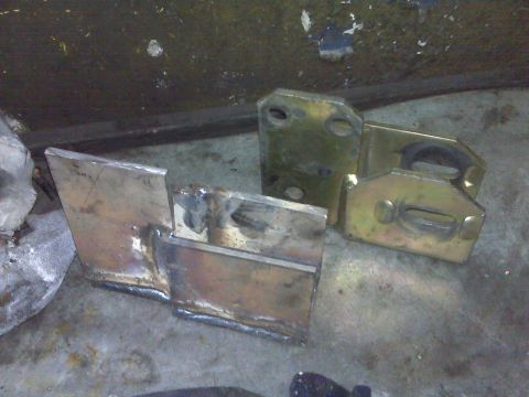 1980 Ford Bronco - Custom fabricated metal parts, likely for a vehicle suspension system, are laid out on a workshop floor.
