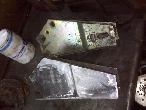 1980 Ford Bronco - Two metal components, likely for a lift kit, are shown in a workshop setting.