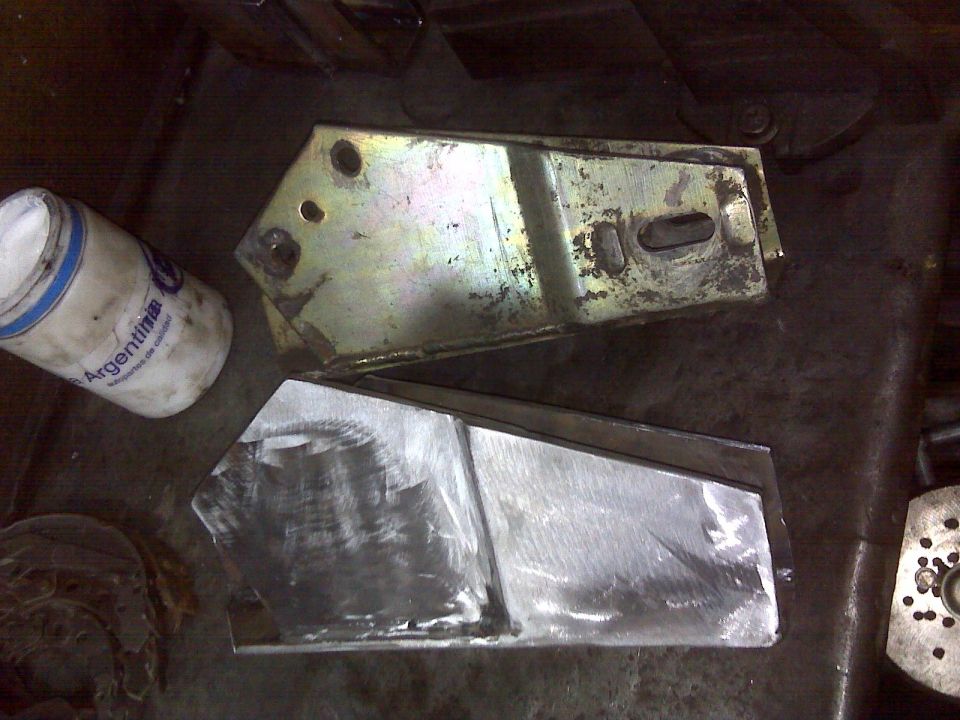 Two metal lift kit components, one with yellowing finish, the other raw metal
