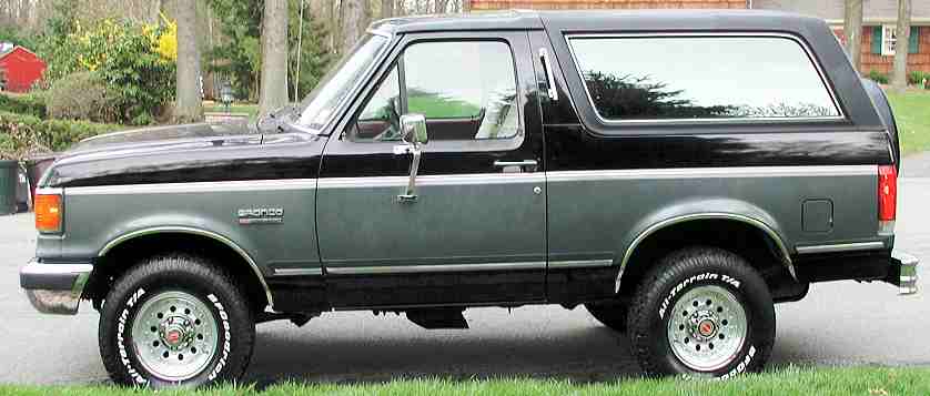 Side view of a black and gray 1989 Ford Bronco parked on grass