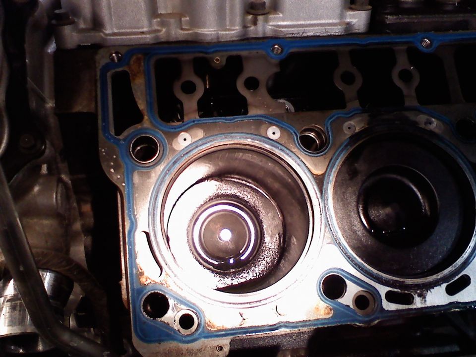 Open engine block with cylinder bores, pistons and blue head gasket