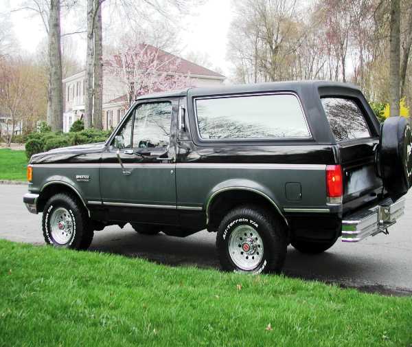Black two-door SUV with gray lower cladding parked on driveway, rear-three-quarter view