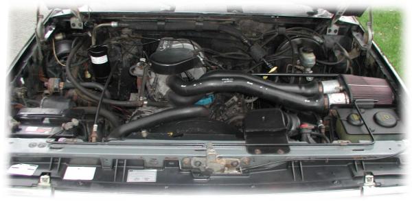 Engine bay of a Ford Bronco showing V8 engine with aftermarket red cone air filter intake