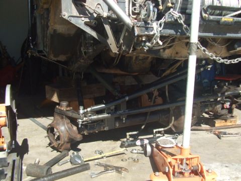 1994 Jeep Cherokee - Custom suspension work is underway on this off-road vehicle, with parts laid out on the ground.