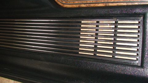 1979 Ford Bronco - Close-up of a vehicle's interior door panel, showing a chrome vent and wood grain trim.