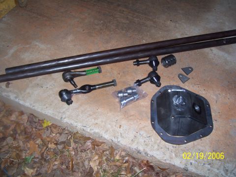 1978 Ford Bronco - Various automotive steering and differential parts are arranged on a concrete surface.