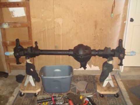 1992 Ford Bronco - Front axle assembly for a Ford Bronco, supported by jack stands in a garage setting.