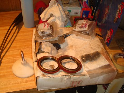 1992 Ford Bronco - Two red and black oil seals are visible on a cardboard box, surrounded by various other automotive parts and supplies.