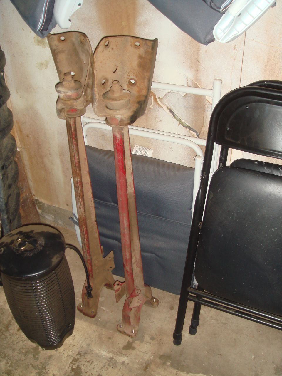 Two rusty metal suspension parts with red painted shafts and mounting plates