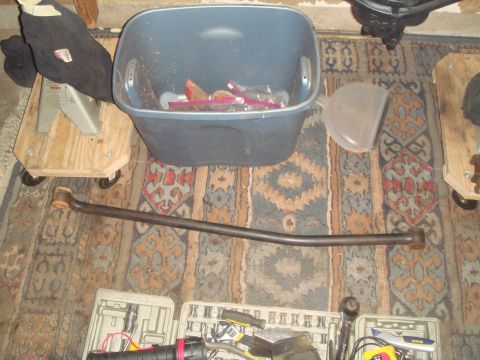 1992 Ford Bronco - A single automotive part is laid out on a rug, surrounded by tools and a storage bin.