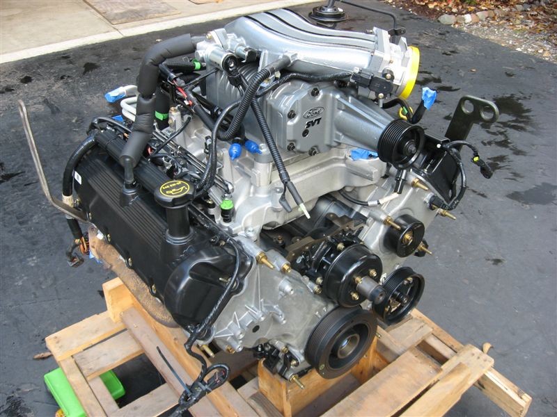 Ford SVT supercharged engine on a wooden pallet. Has a silver intake manifold and black valve covers
