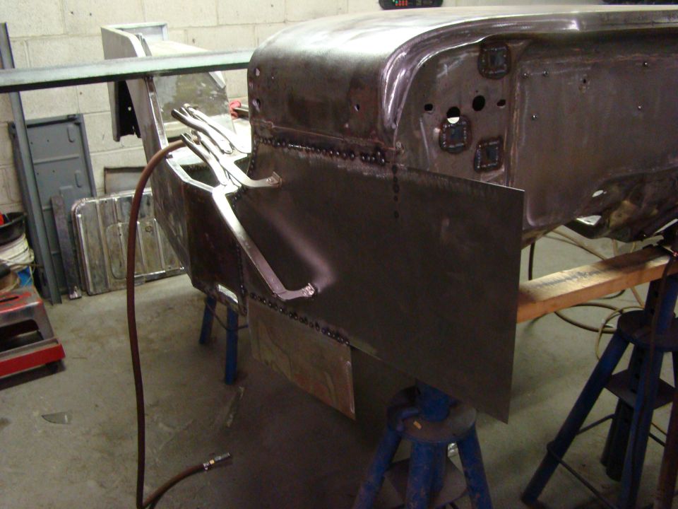 vehicle body on jack stands with metal panel being welded on