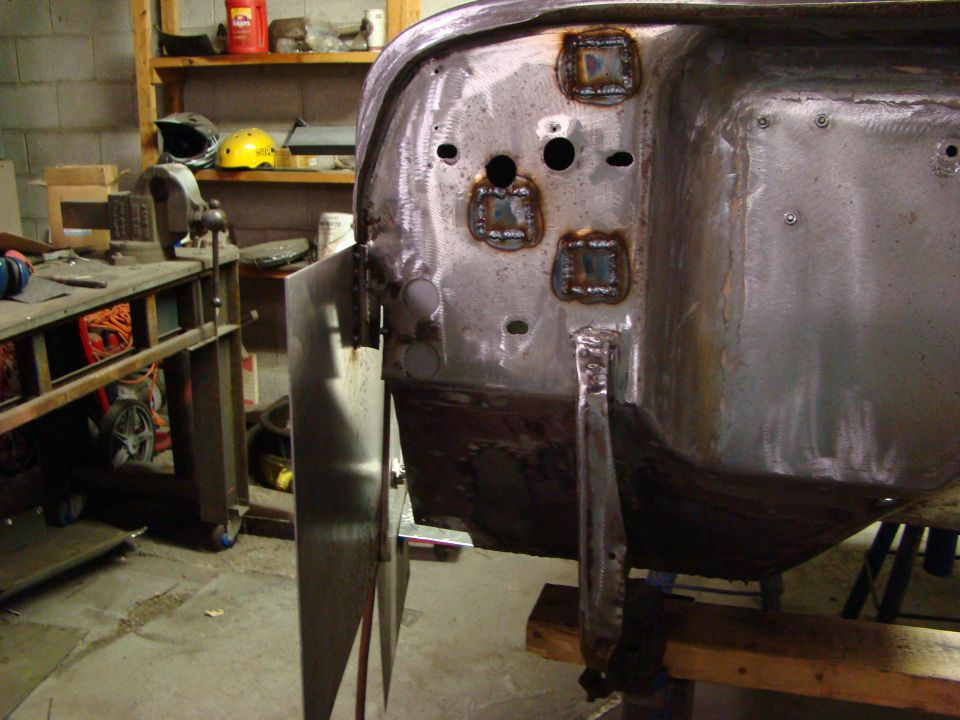 Welded patches on bare metal vehicle body panel in workshop