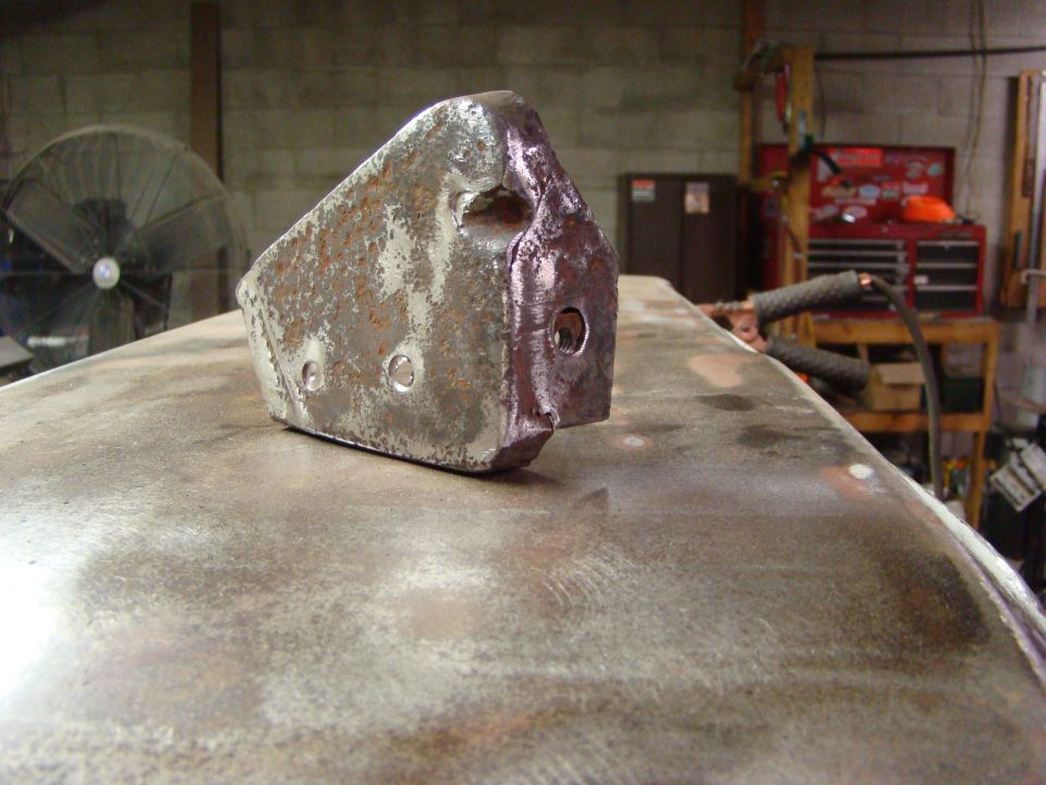 metal part with rust and holes on a metal surface, workshop in background