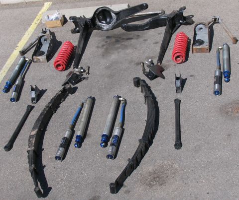 1984 Ford Bronco - A collection of vehicle suspension components, including shocks and leaf springs, are displayed on the ground.