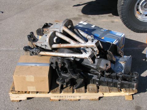 1984 Ford Bronco - A collection of vehicle suspension components, including leaf springs and control arms, are piled on a pallet.
