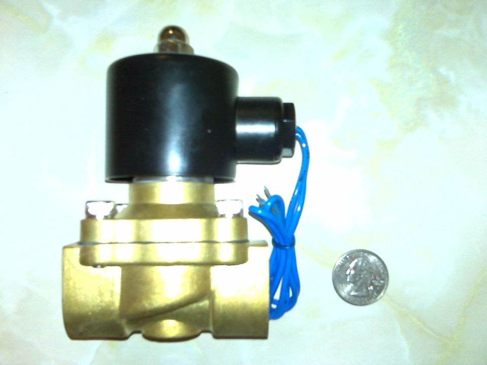 Brass solenoid valve with black coil and blue wires next to a quarter for scale