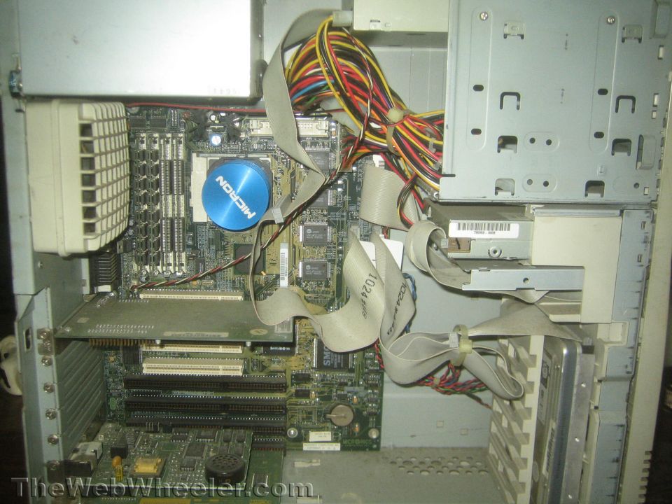 Computer motherboard with CPU fan, RAM slots, and ribbon cables. Micron logo visible on fan