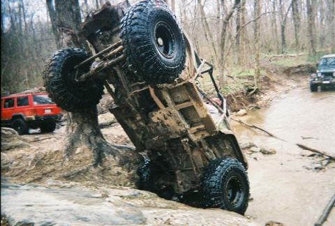 1992 Ford Bronco - An off-road vehicle is stuck against a tree during an off-road excursion.