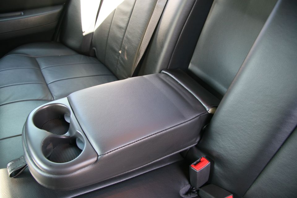 Black rear seat with fold-down center armrest and dual cup holders in a car interior