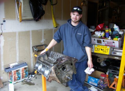 1978 Ford Bronco - A man stands with a disassembled engine block in a garage setting, with various tools and supplies visible.