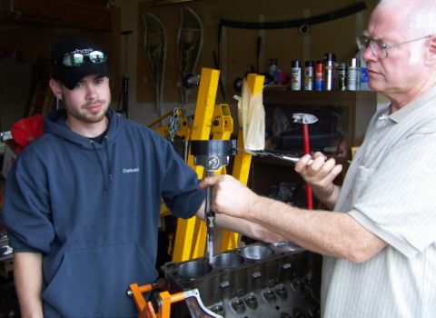 1978 Ford Bronco - Two men work on an engine block in a garage setting.