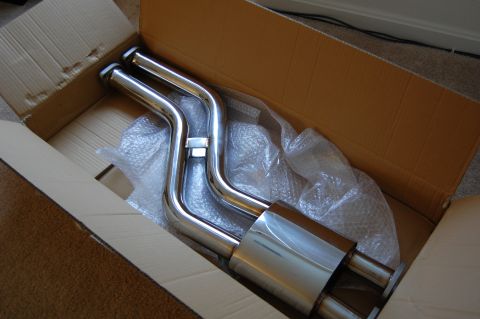 2002 BMW M3 - A new chrome exhaust system is shown packaged in a cardboard box, ready for installation.