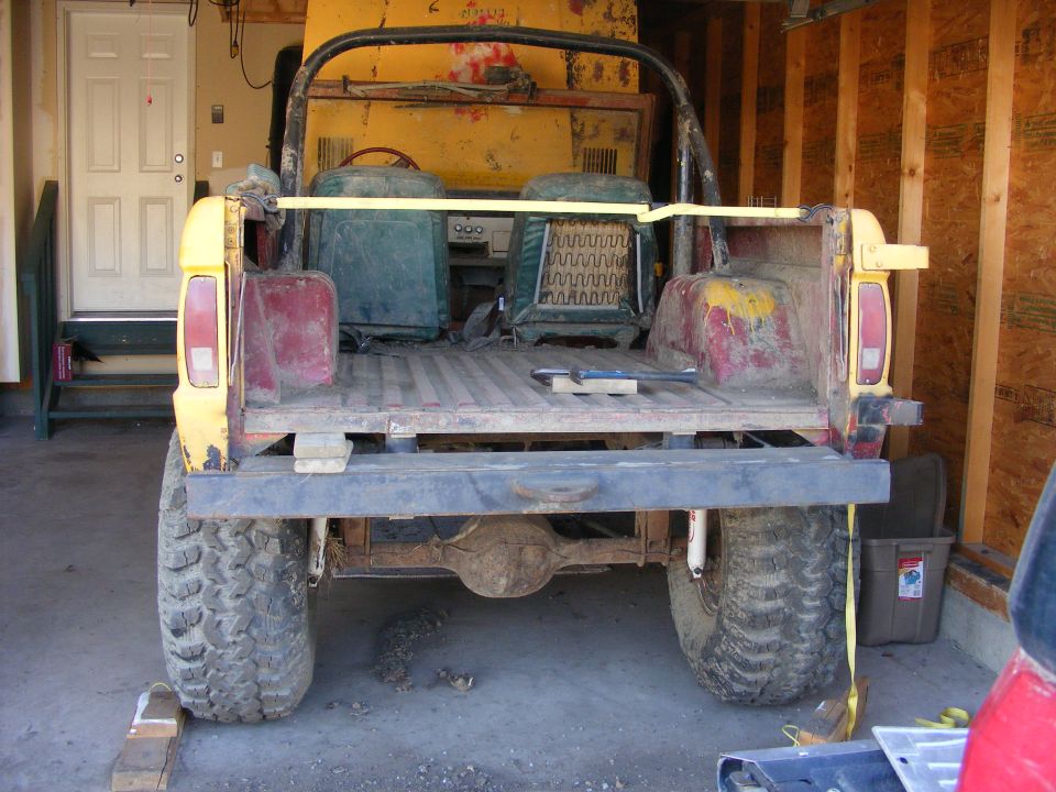 Rear view of a yellow 1974 Ford Bronco with red accents and large tires