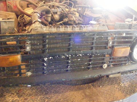 1974 Ford Bronco - Close-up view of a vehicle's engine compartment and front grille, showing mechanical components and radiator.