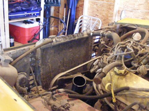 1974 Ford Bronco - The engine bay of a yellow vehicle is shown, with a focus on the radiator and surrounding engine components.