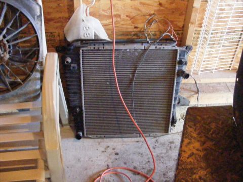 1974 Ford Bronco - A vehicle radiator sits on the floor, with electrical cords and a fan visible nearby.