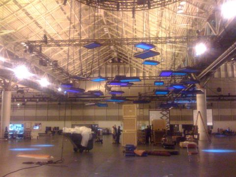 1994 Ford Bronco - The interior of a large venue is set up with lighting rigs and stacked crates, suggesting an event preparation.