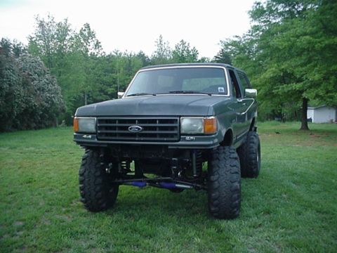 1987 Ford Bronco - This lifted 1987 Ford Bronco sits on a grassy area with trees in the background.