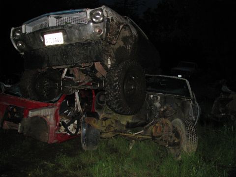 1978 AMC Javelin - Two heavily damaged cars are piled up, one on top of the other, in a dark, grassy area.