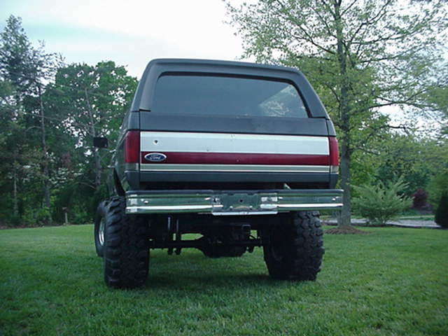Rear of lifted dark gray Ford Bronco on large tires parked on grass