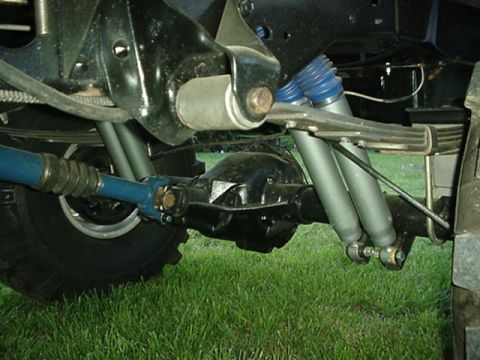 1987 Ford Bronco - Close-up view of the rear axle and suspension system on a 1987 Ford Bronco, highlighting the blue shocks and leaf springs.