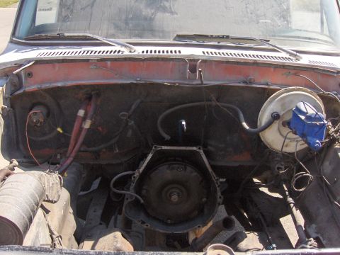 1978 Ford Bronco - The engine bay of a vehicle is shown with the transmission removed, revealing internal components and wiring.