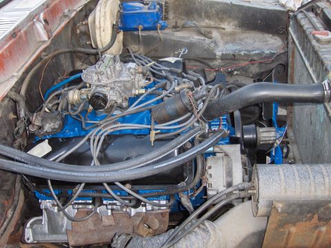 1978 Ford Bronco - Engine bay detail showing a blue painted engine block, carburetor, and various hoses and wires.