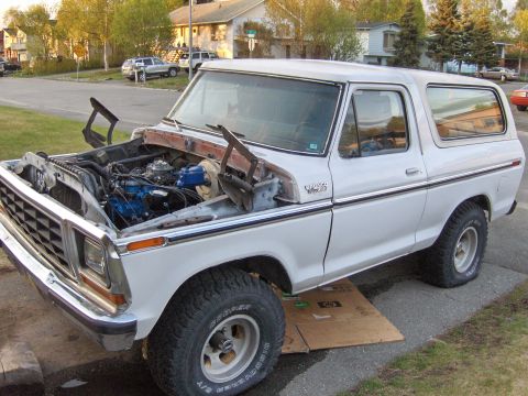 1978 Ford Bronco - White 1978 Ford Bronco with hood open, engine exposed, parked on cardboard.
