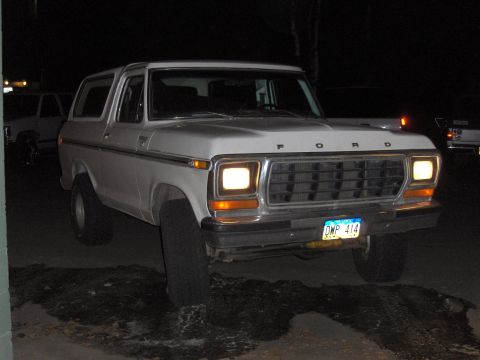 1978 Ford Bronco - A white 1978 Ford Bronco is parked outside at night, showing its front grille and headlights.