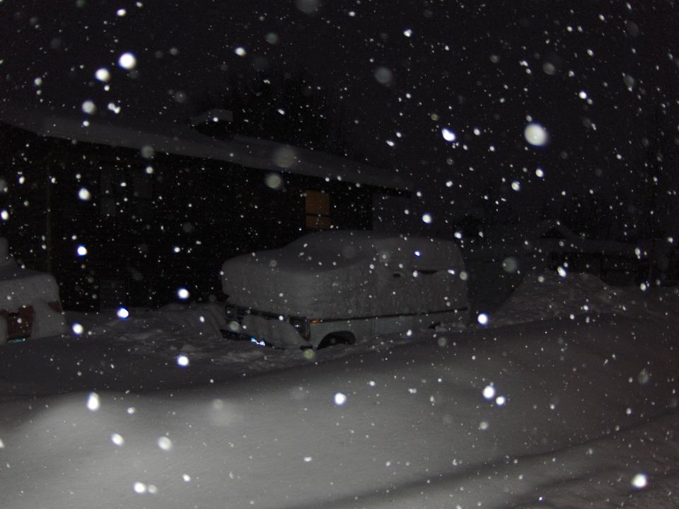 Snow-covered vehicle at night during a heavy snowfall