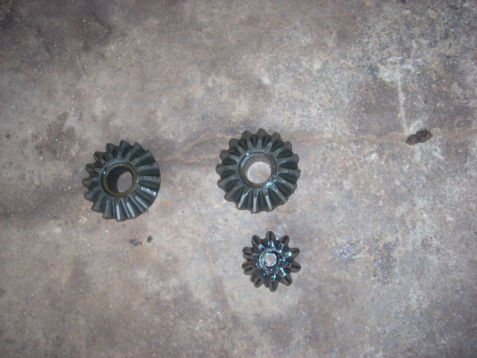 Three metal differential gears on a concrete surface