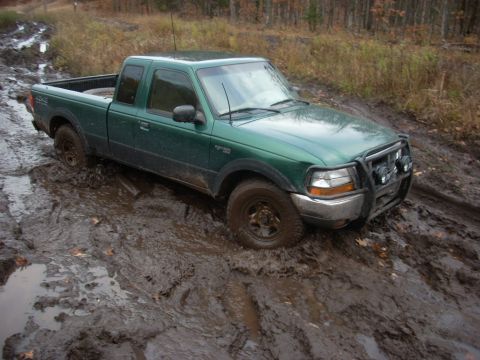 1988 Chevrolet Blazer - This green pickup truck is stuck deep in the mud, its front tires submerged and a brush guard attached.