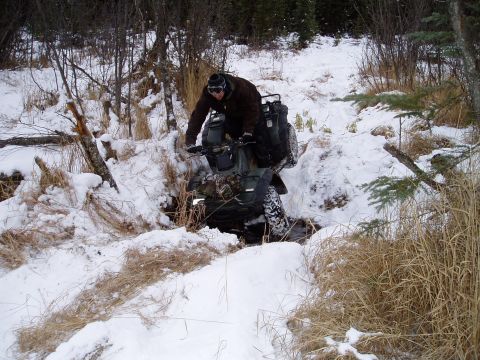 2000 Ford E350 - An ATV navigates a challenging snowy terrain, with a rider dressed for cold weather.